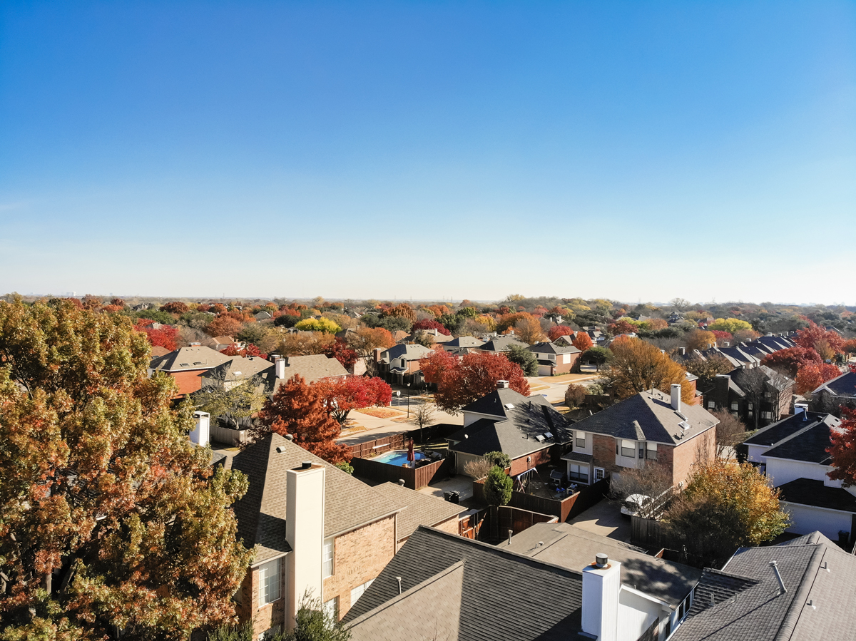 Aerial view beautiful neighborhood in Coppell, Texas, USA in autumn season. Row of single-family home with attached garage, garden, swimming pool surrounded by colorful fall foliage leaves